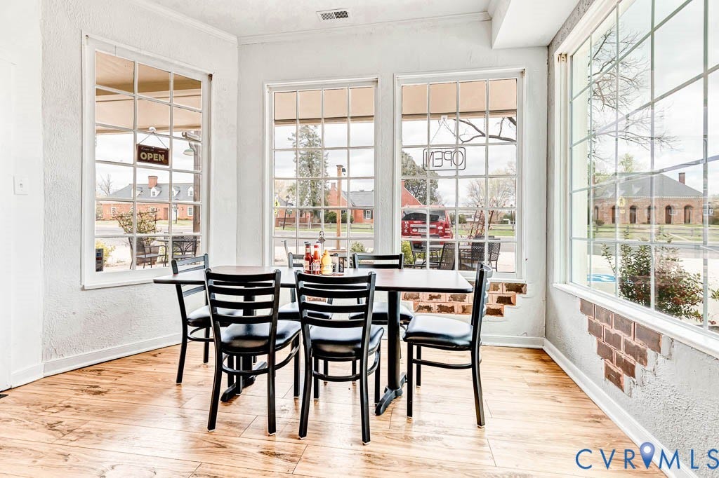 Wood-finish flooring with exposed brick accents, large gridded windows, and textured white walls
