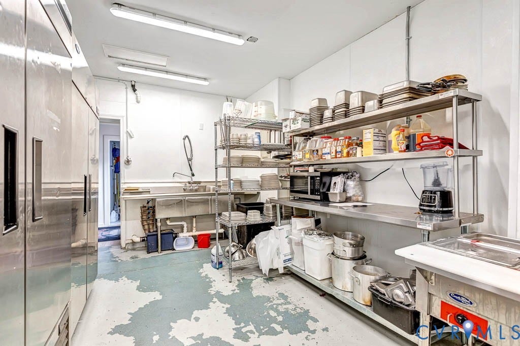 Commercial-grade stainless steel appliances and shelving, ample counter space, multiple sinks, and overhead strip lighting