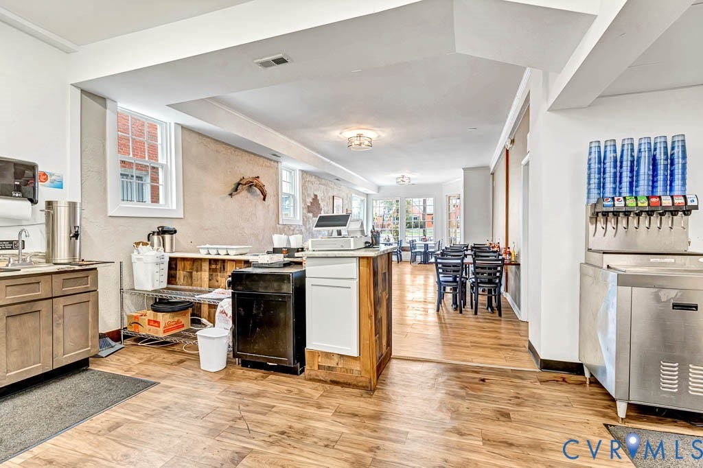 Expansive commercial space featuring wood-finish flooring, recessed lighting, multiple windows, and a built-in beverage station