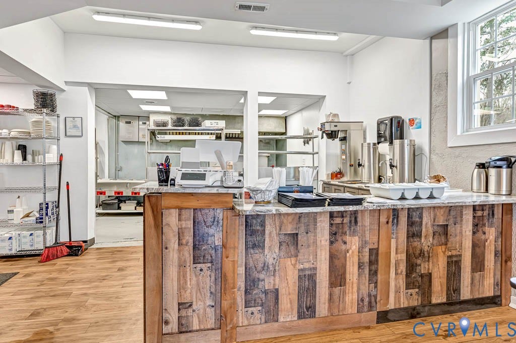 Wood-finish flooring, wood-paneled counter, natural light from a window, and overhead fluorescent lighting fixtures