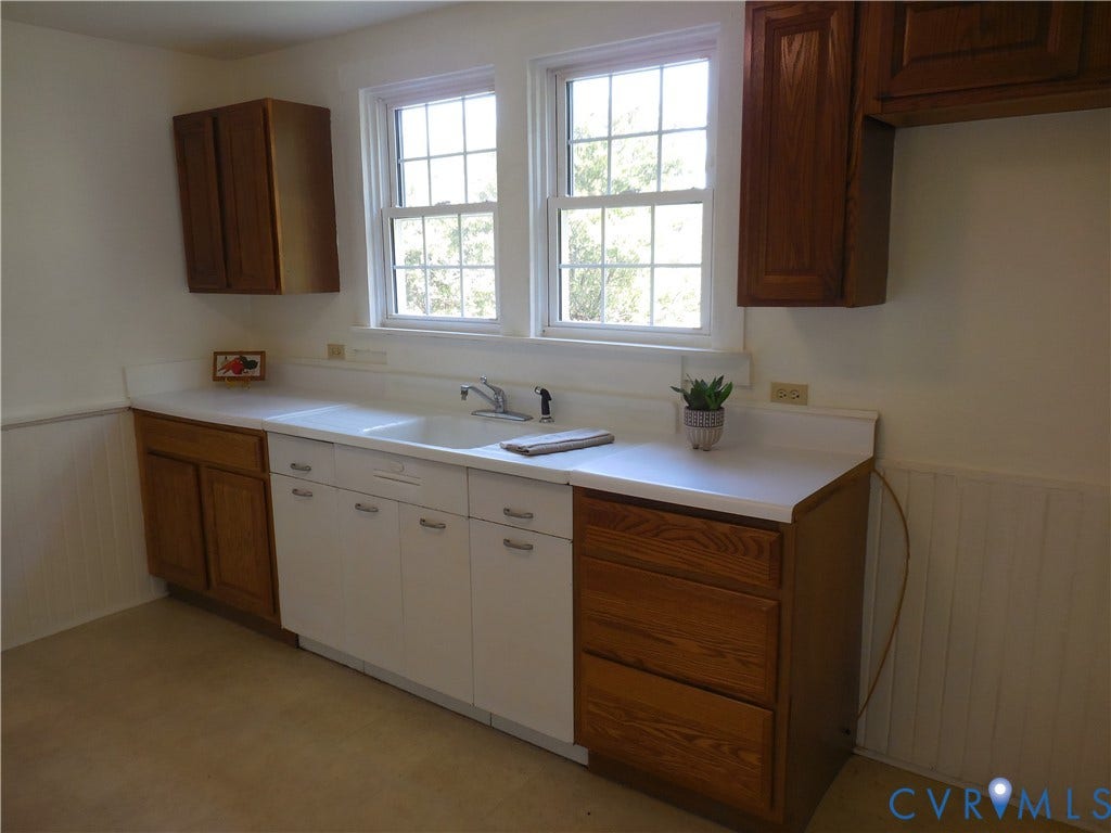 6507 Old Columbia Road, Columbia, Columbia, VA 23038 Dual windows with grid inserts, white countertops, a double basin sink, and wood-finish cabinetry