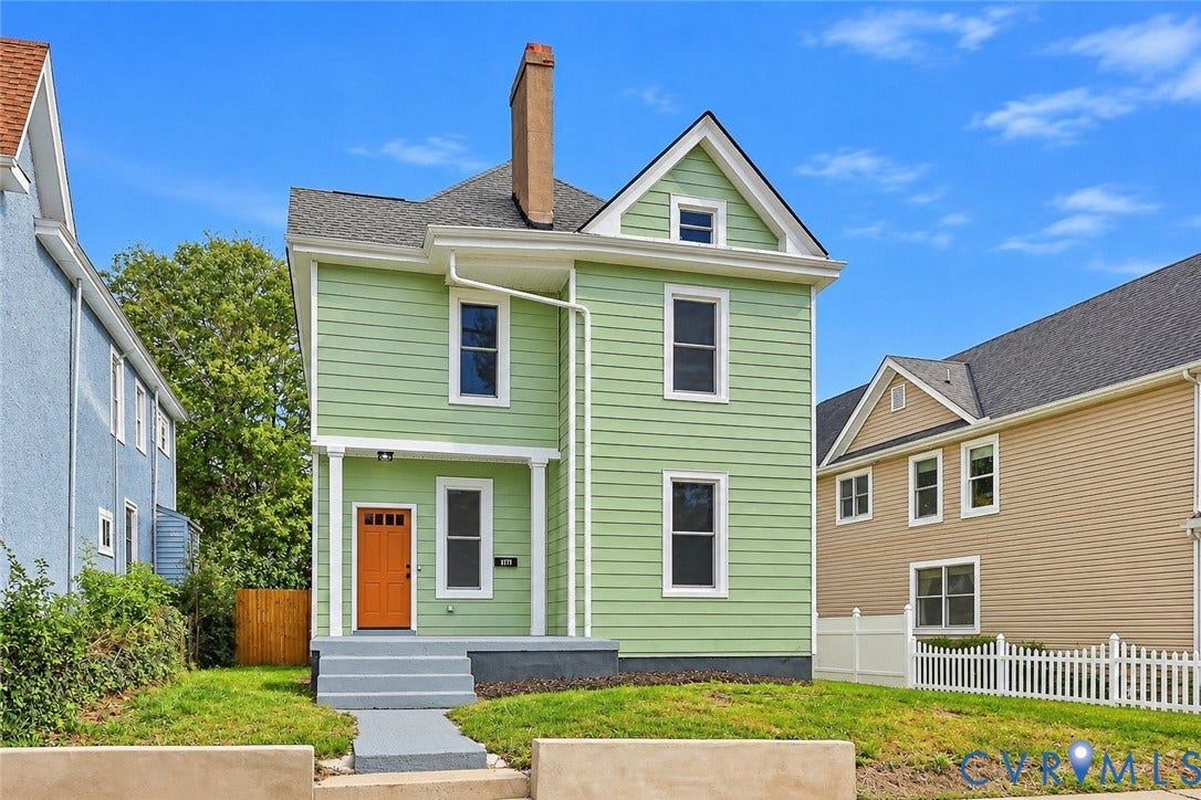 Two-story residence featuring horizontal siding, a central chimney, a covered front porch, and a dedicated walkway