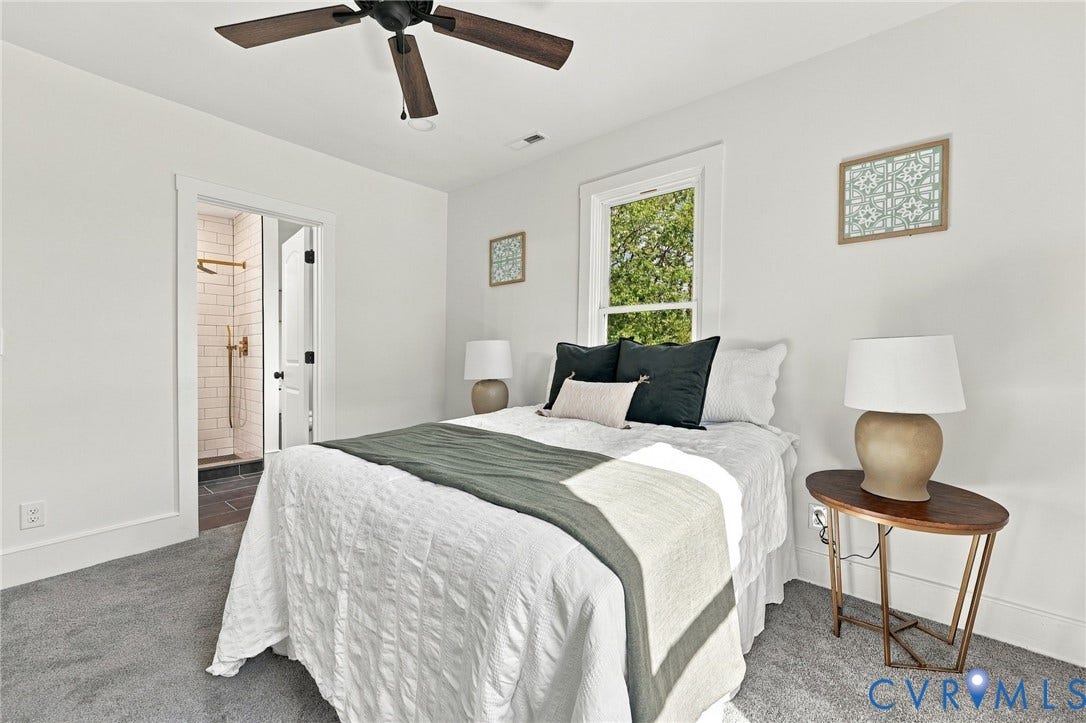 Neutral-toned interior featuring wall-to-wall carpeting, a ceiling fan with wood-finish blades, and a window with white trim