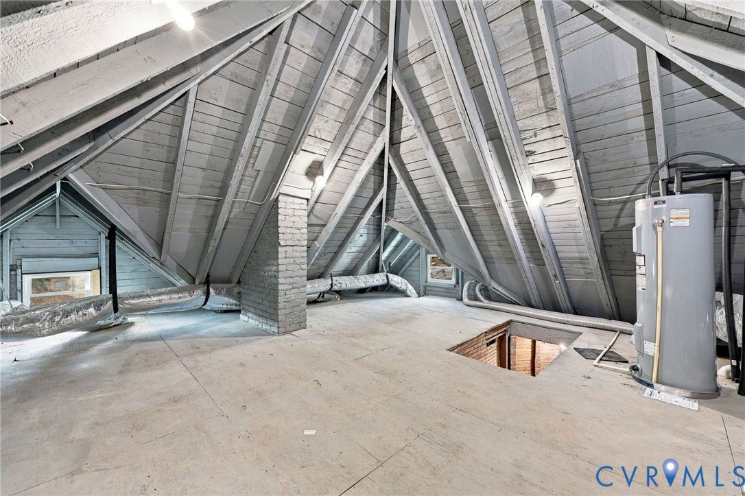 Attic space featuring exposed vaulted rafters, painted wood plank ceiling, brick chimney masonry, and a vertical water heater