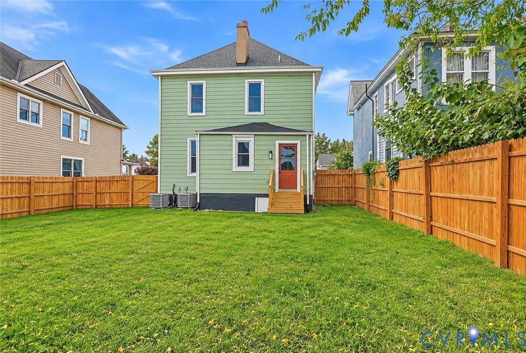 Fenced backyard featuring a manicured lawn, horizontal wood-panel siding, exterior wooden staircase, and central chimney