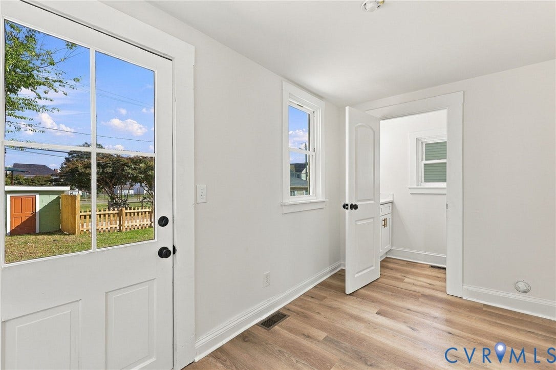 Wood-finish flooring, multi-pane glass door, crisp white interior trim, and double-hung windows