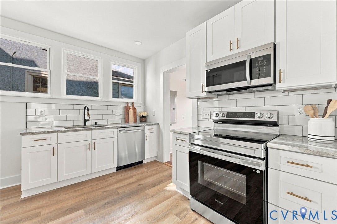 Kitchen featuring white Shaker-style cabinetry, stainless steel appliances, neutral stone-finish countertops, subway tile backsplash, and wood-finish flooring