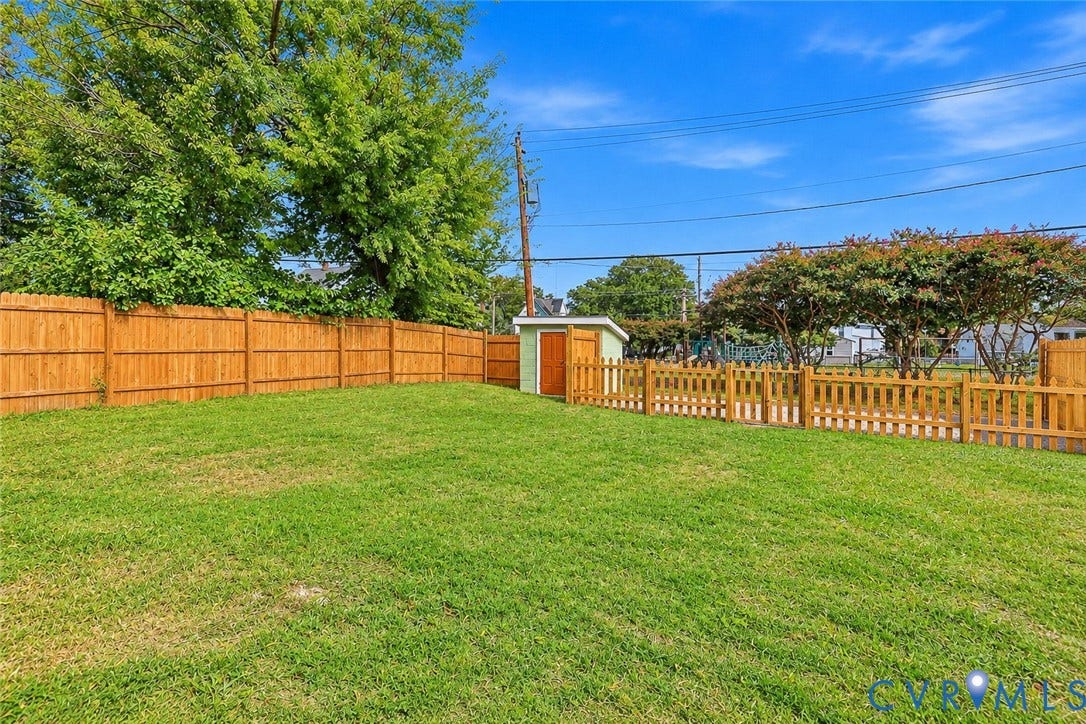 Rear yard featuring manicured lawn, perimeter wood fencing, and a detached storage structure