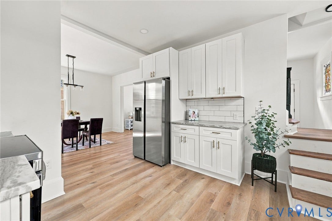 Kitchen featuring white cabinetry, stone-finish countertops, a white subway tile backsplash, stainless steel refrigerator, and wood-finish flooring