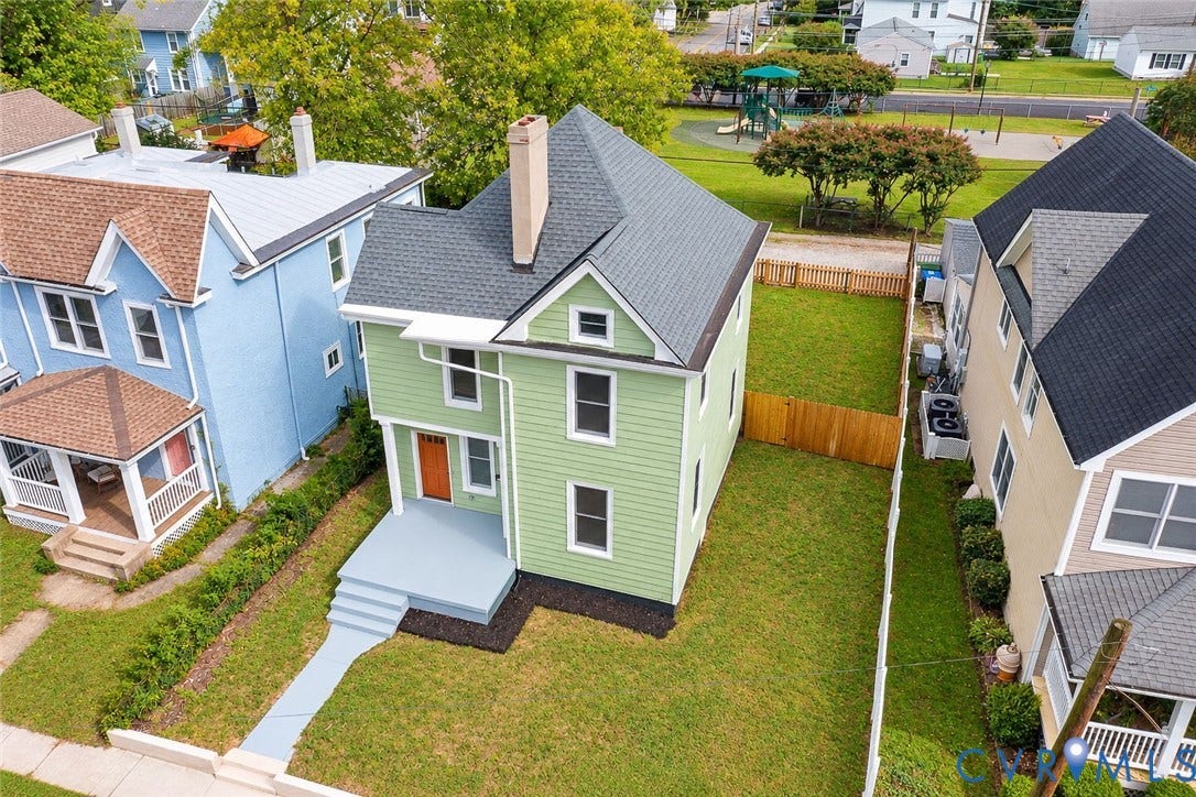 Two-story residence featuring lap siding, an asphalt shingle roof, a central chimney, a front entry porch with steps, and a fenced backyard