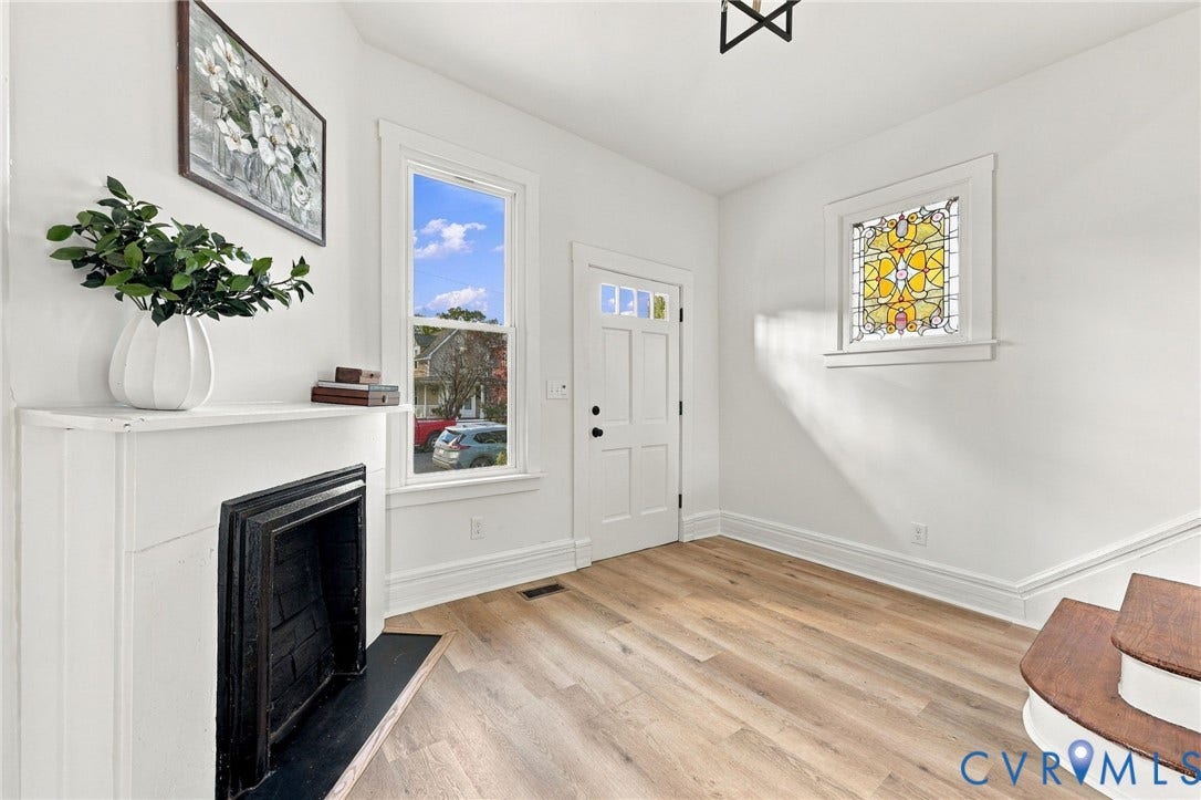 Fireplace with a black hearth, wood-finish flooring, stained-glass window, and a multi-panel door with glass inserts