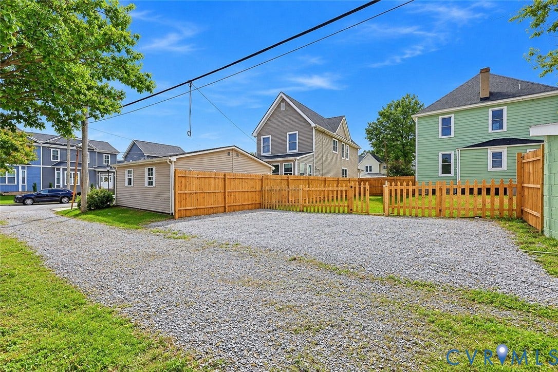 Gravel parking area with a detached garage and a wood privacy fence