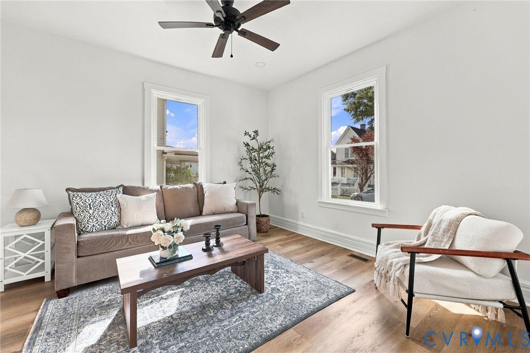 Interior space featuring wood-finish flooring, two double-hung windows, and a ceiling fan