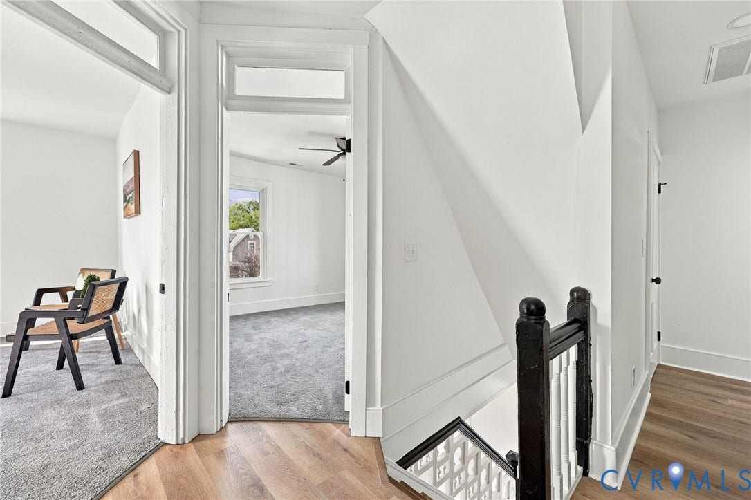 Staircase featuring a decorative black handrail with white balusters, wood-finish flooring, and interior door frames with transom windows