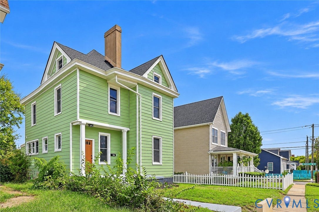 Two-story residence featuring lap siding, prominent gables, a central chimney, and a covered entry porch