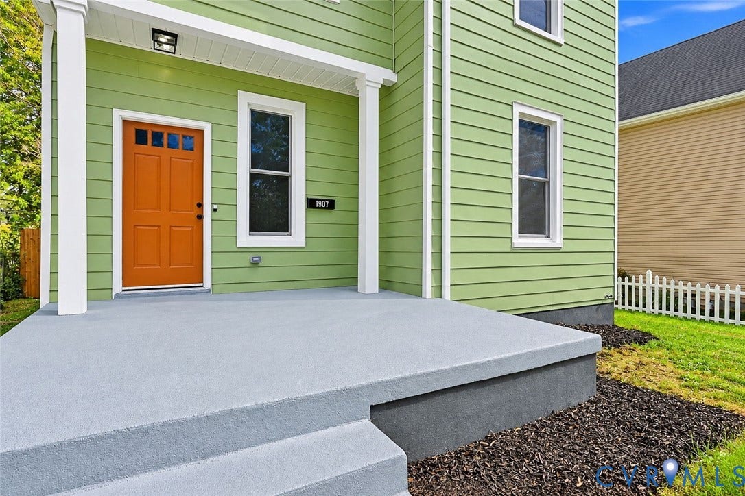 Horizontal lap siding exterior with a covered front porch, concrete stoop, and an orange-paneled entry door