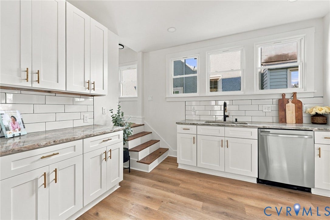 Kitchen featuring white shaker-style cabinetry, stone-finish countertops, subway tile backsplash, stainless steel dishwasher, and wood-finish flooring