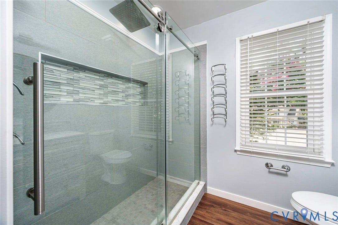 4605 English Cedar Court, Glen Allen, VA 23060 Glass-enclosed shower with a rainfall showerhead, linear tile accent, and built-in shelving