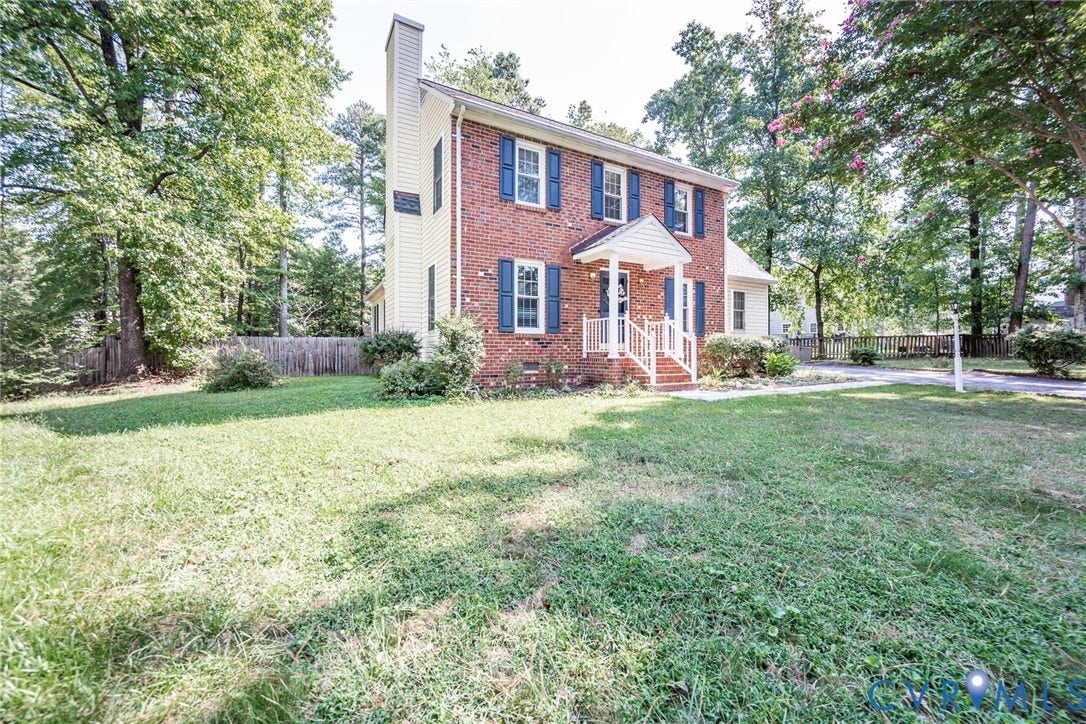 4605 English Cedar Court, Glen Allen, VA 23060 Two-story brick and siding exterior with blue window shutters, featuring a covered front entry with white columns and railings, a brick chimney, and mature trees