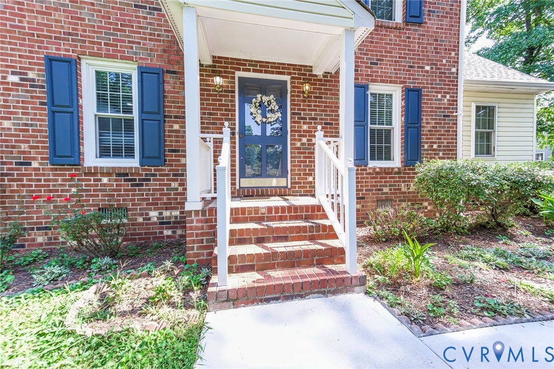 4605 English Cedar Court, Glen Allen, VA 23060 Brick facade with blue window shutters, concrete walkway, covered porch, and white railing