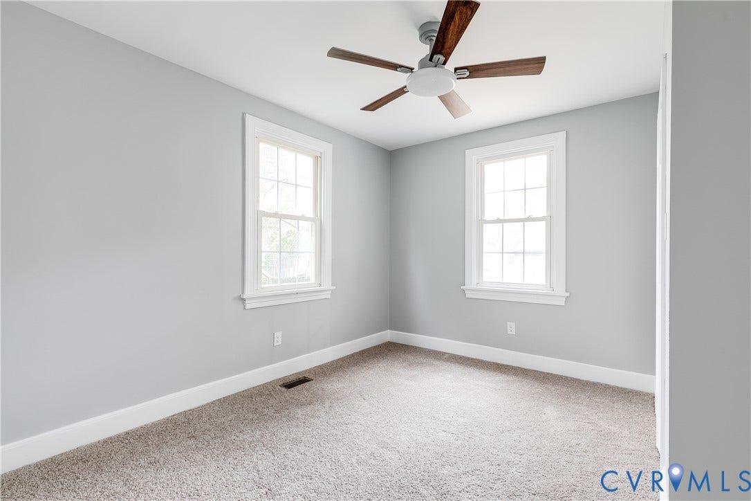 2012 Bailey Avenue, Richmond, VA 23231 Neutral gray wall tones, two double-hung windows with white trim, and a ceiling fan with wood-finish blades