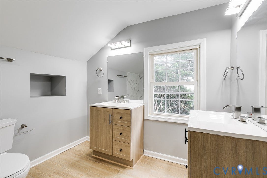 2012 Bailey Avenue, Richmond, VA 23231 Sloped ceiling bathroom featuring wood-finish flooring, a built-in wall niche, vanity with undermount sink and white countertop, and a double-hung window
