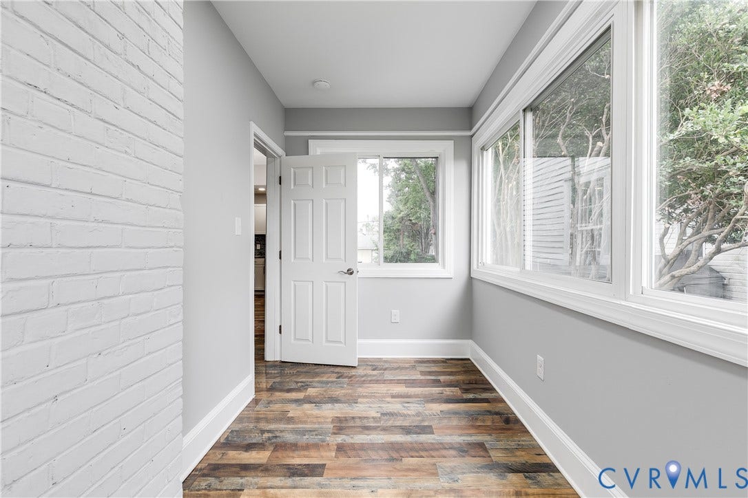 2012 Bailey Avenue, Richmond, VA 23231 Wood-finish flooring, white trim, multiple windows with white frames, white interior door, and painted brick wall