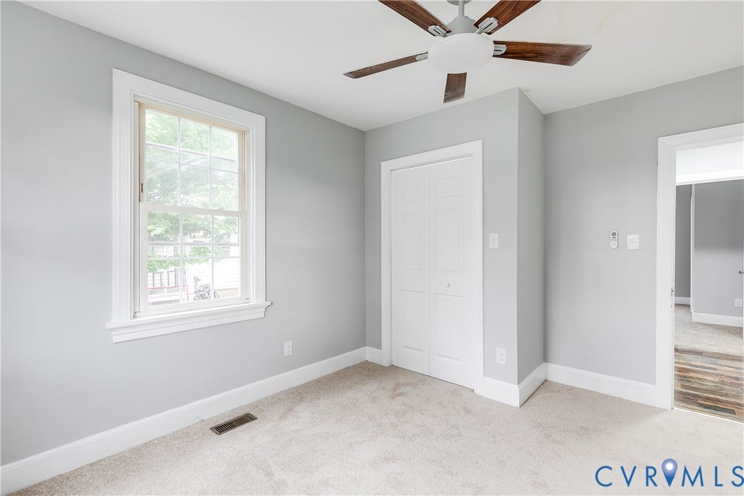2012 Bailey Avenue, Richmond, VA 23231 Light gray wall paint, textured carpeting, white trim, a double-hung window, and a ceiling fan with wood-finish blades