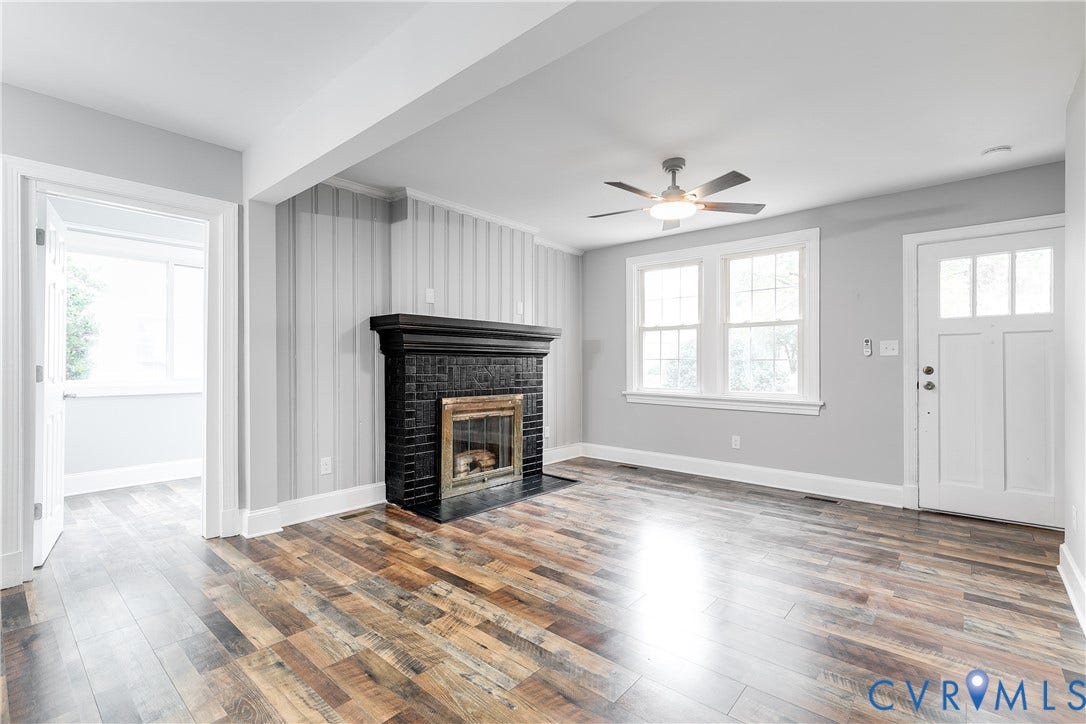 2012 Bailey Avenue, Richmond, VA 23231 Rich wood-finish flooring, a decorative fireplace with a dark mantel, white trim, a ceiling fan with integrated lighting, and a paneled entry door with transom lites