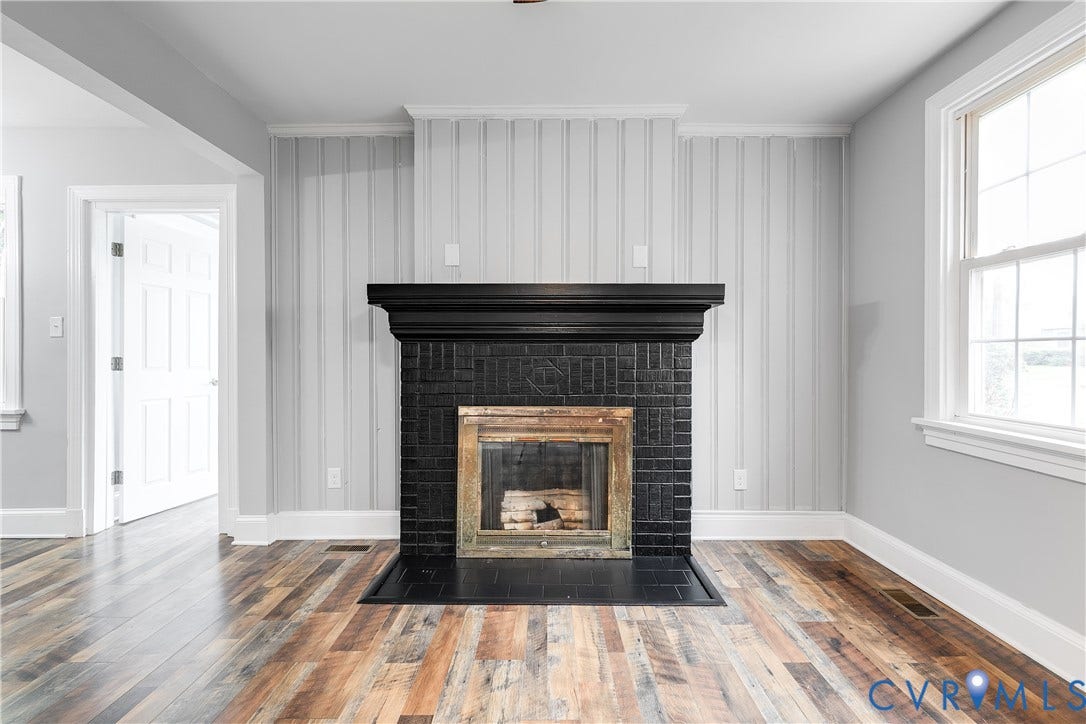 2012 Bailey Avenue, Richmond, VA 23231 Fireplace with a black brick surround and mantel, wood-finish flooring, paneled wall accent, and white trim throughout