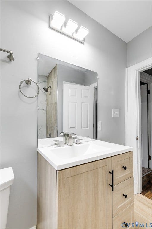 2012 Bailey Avenue, Richmond, VA 23231 Floating vanity with a white countertop and integrated sink, brushed nickel faucet, and natural wood-finish cabinetry with black hardware