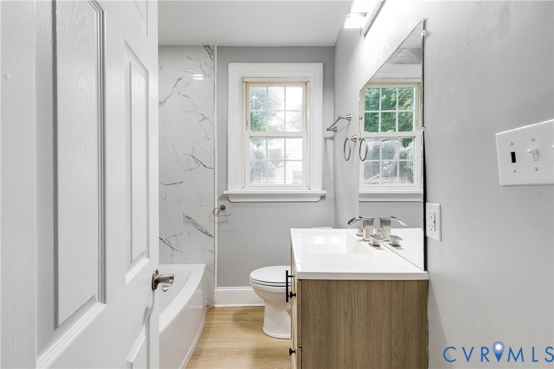 2012 Bailey Avenue, Richmond, VA 23231 White bathroom featuring a single window, a wood-finish vanity with a white countertop, and a shower with marble-look wall tiling