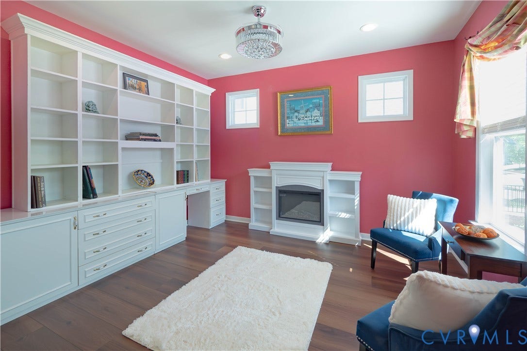 Built-in shelving with integrated desk, electric fireplace, wood-finish flooring, recessed lighting, and a chandelier