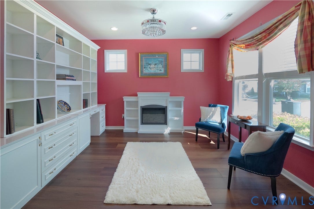 Built-in white cabinetry with a desk area, recessed lighting, wood-finish flooring, and a decorative fireplace with a mantel