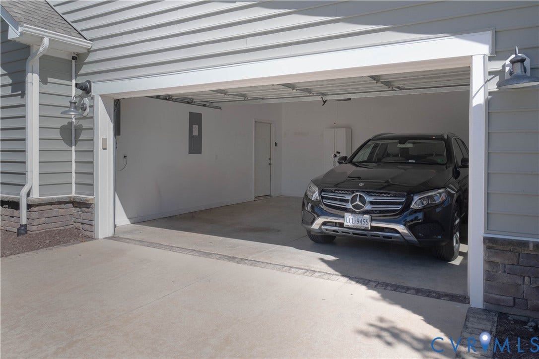 Attached garage with concrete flooring, wall-mounted utility panel, and exterior lantern lighting