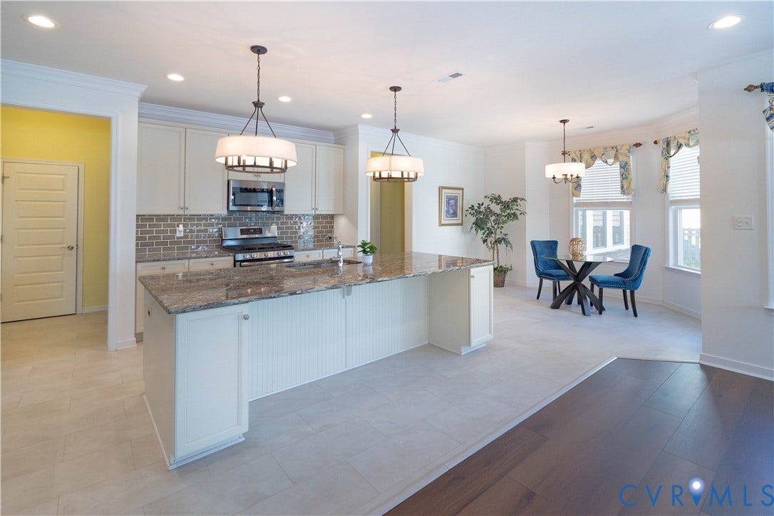 Kitchen featuring an expansive island with granite countertops, stainless steel appliances, and a tile backsplash