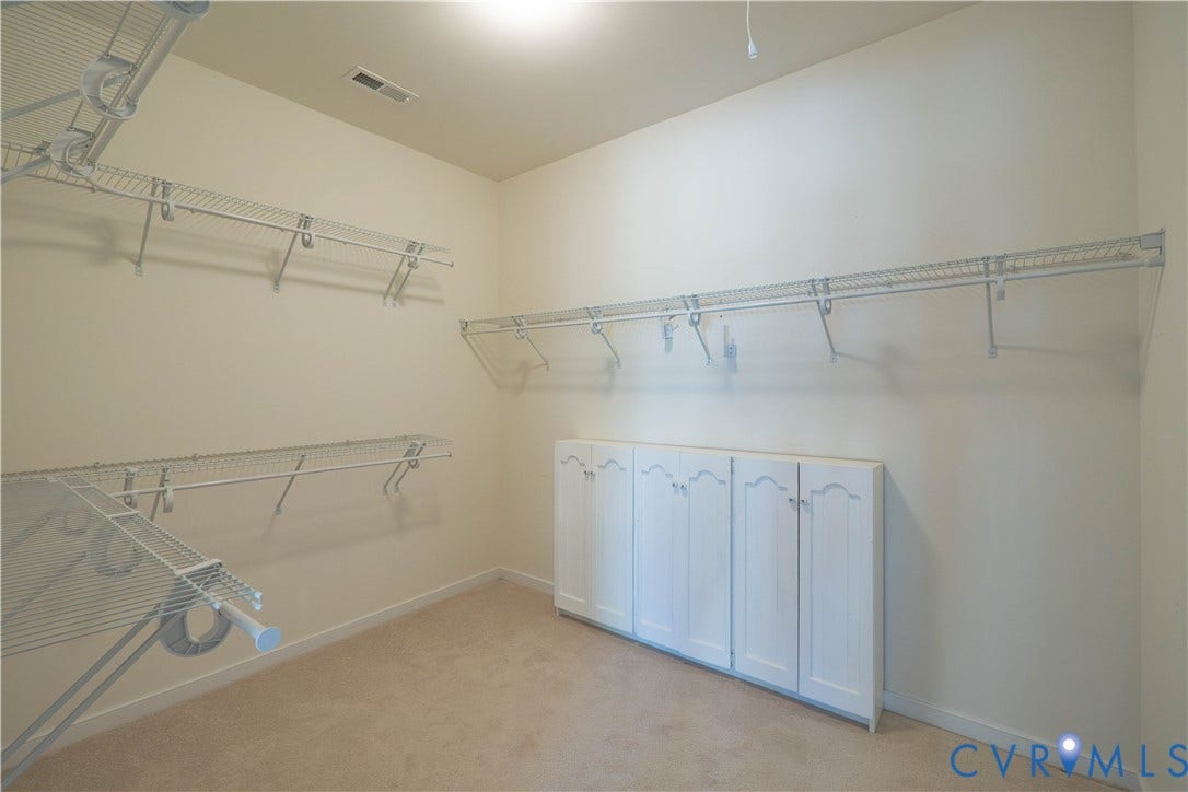 Built-in wire shelving system, integrated wall cabinetry with white panel doors, recessed ceiling lighting, and carpeted flooring