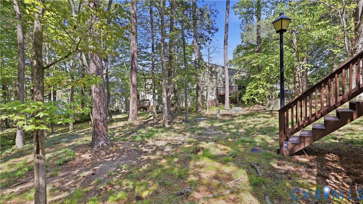 2203 Rockwater Terrace, Henrico, VA 23238 Wooded lot featuring mature trees, a sloped terrain, and a permanent exterior staircase with railing