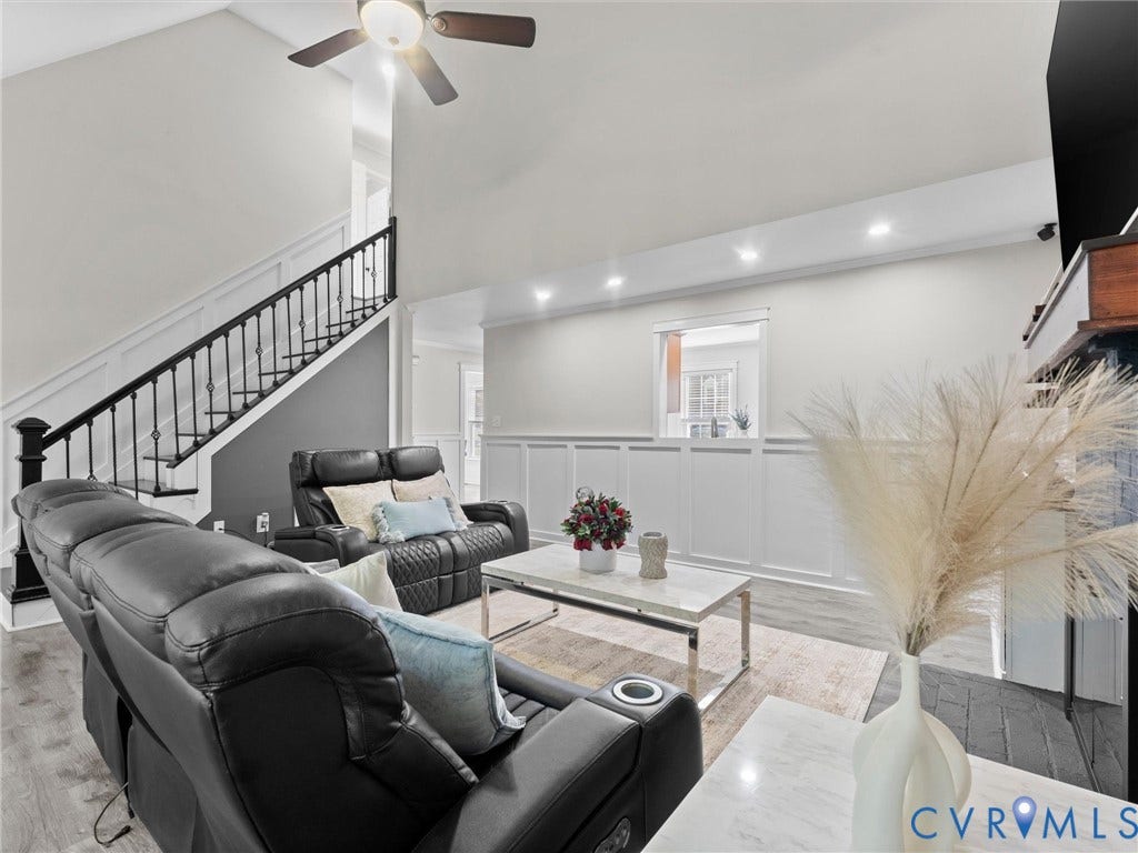 Two-story living area featuring a ceiling fan, recessed lighting, and a staircase with black wrought iron spindles