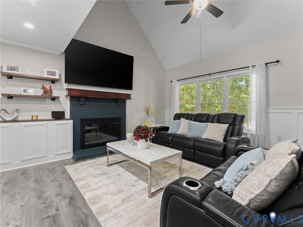 Vaulted ceiling with a ceiling fan, recessed lighting, wood-finish flooring, built-in fireplace, and built-in shelving with cabinetry
