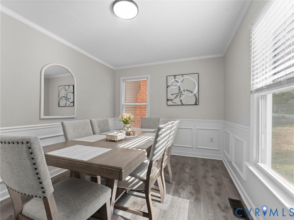 Crown molding, wainscoting, wood-finish flooring, recessed lighting, and a large window