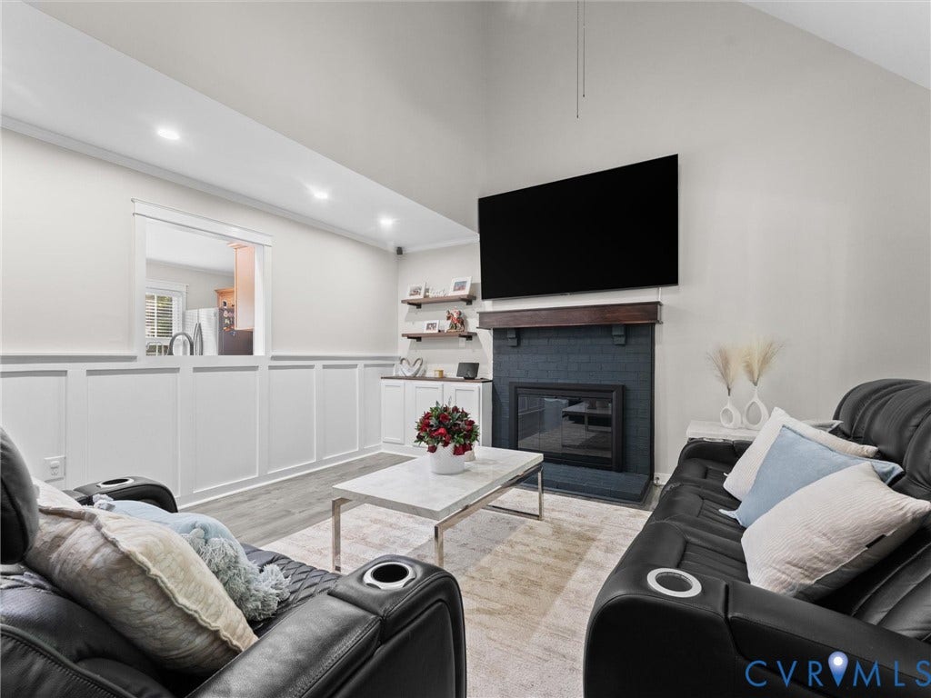 Vaulted ceiling, recessed lighting, fireplace with dark tile surround and wood mantel, built-in cabinetry, and wainscoting