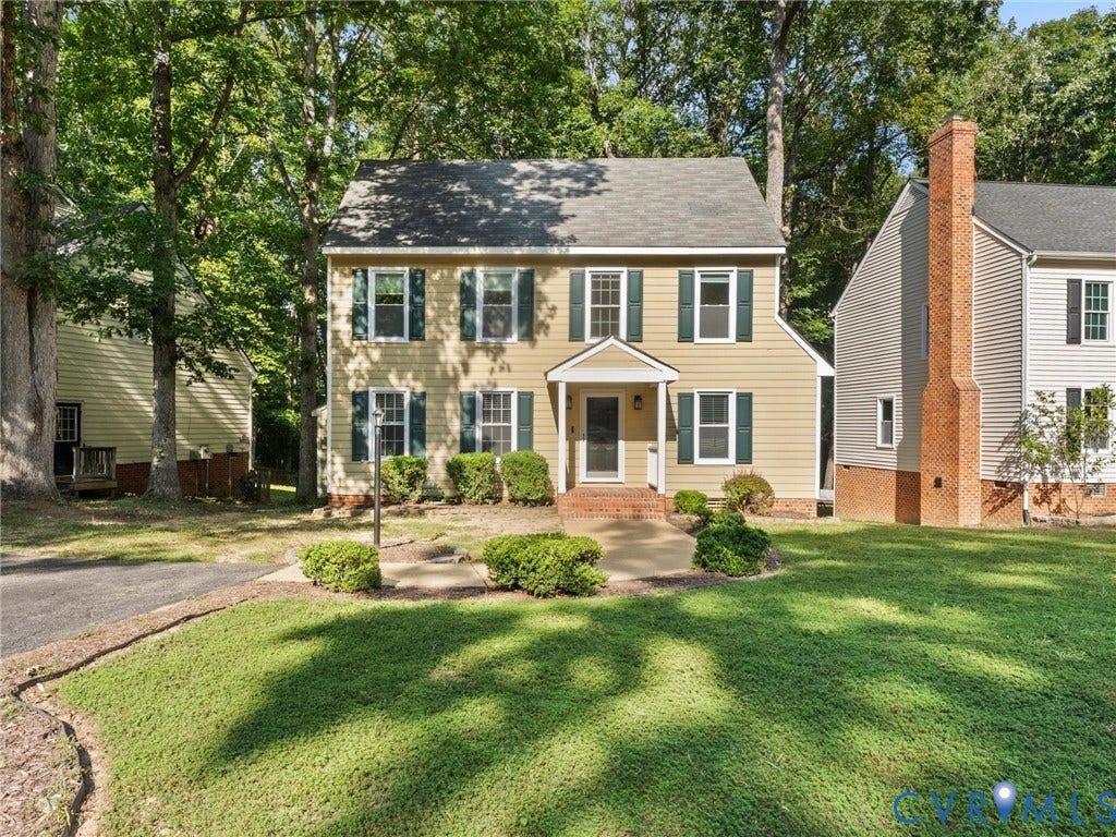 Two-story residence featuring light-colored siding, green shutters, and a covered entry
