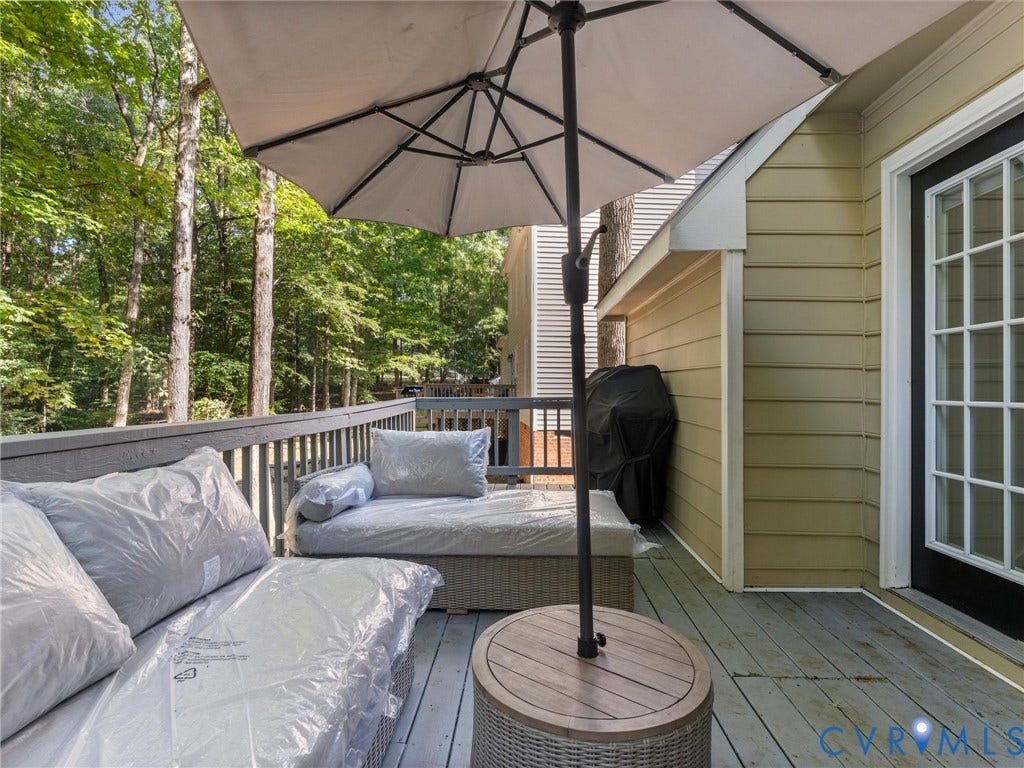 Wood-finish deck with a wood railing and a treed backdrop