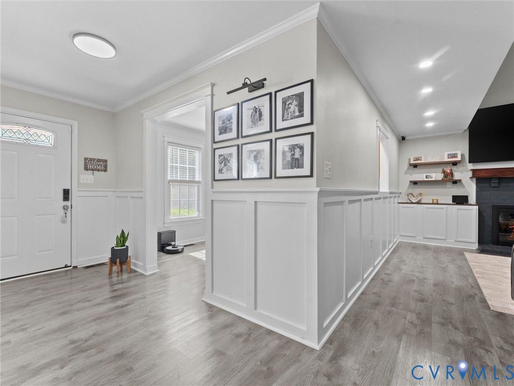 Wood-finish flooring throughout, white board and batten wall paneling, white trim and crown molding, recessed lighting, and built-in white cabinetry with open shelving