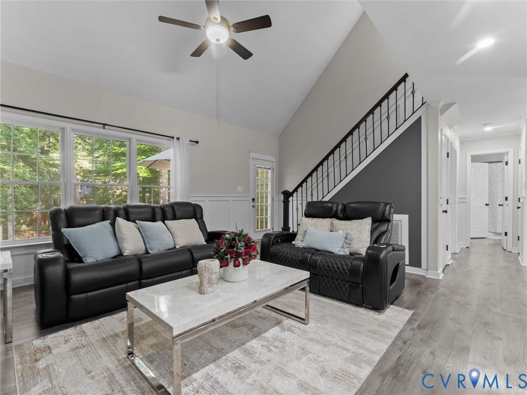 Vaulted ceiling with a ceiling fan, recessed lighting, wood-finish flooring, and a staircase featuring wrought iron balusters