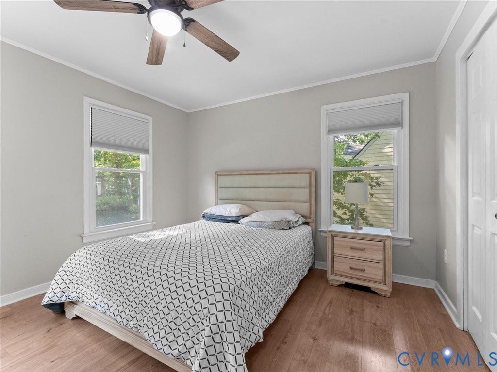 Wood-finish flooring, white trim, and a ceiling fan with integrated lighting