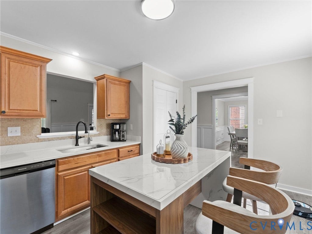 Kitchen featuring wood-finish cabinetry, stainless steel dishwasher, and a center island with a stone-finish countertop
