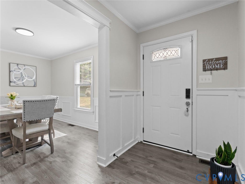 Entryway featuring a decorative front door with transom window, wood-finish flooring, and wainscoting