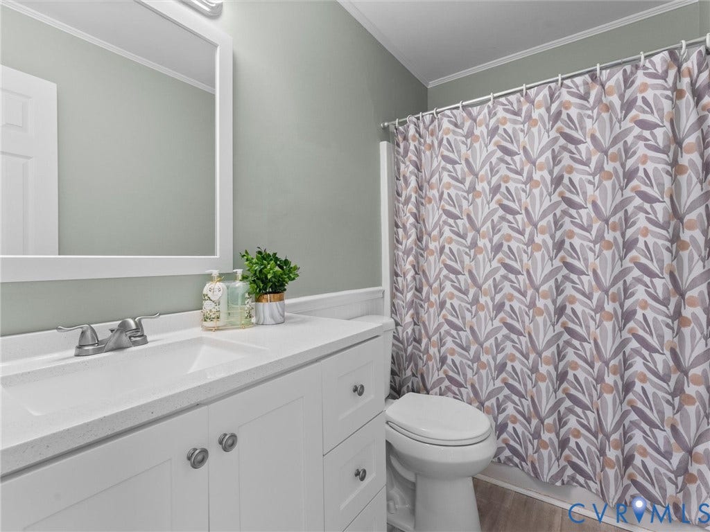 White vanity with a single basin sink, white countertop, and framed mirror
